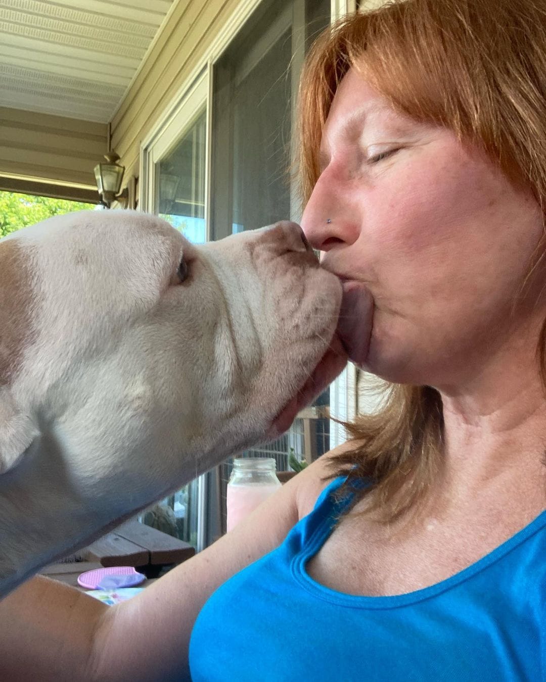 old woman kissing a dog